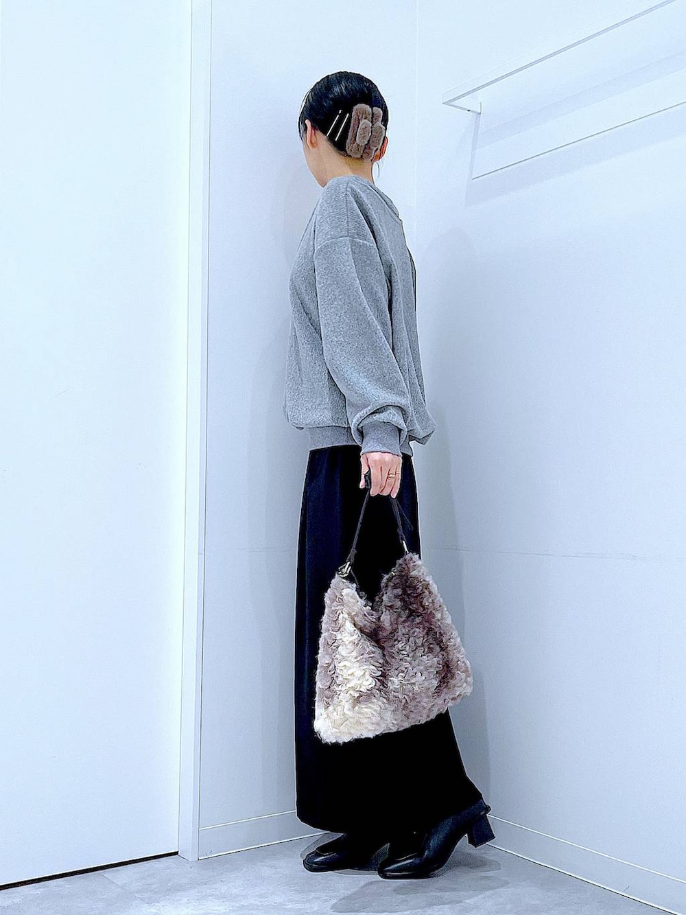 ブラック系のスカート、ブラック系のブーツ、ブラウン系のショルダーバッグを着用したレディースの冬コーディネートの3枚目の写真