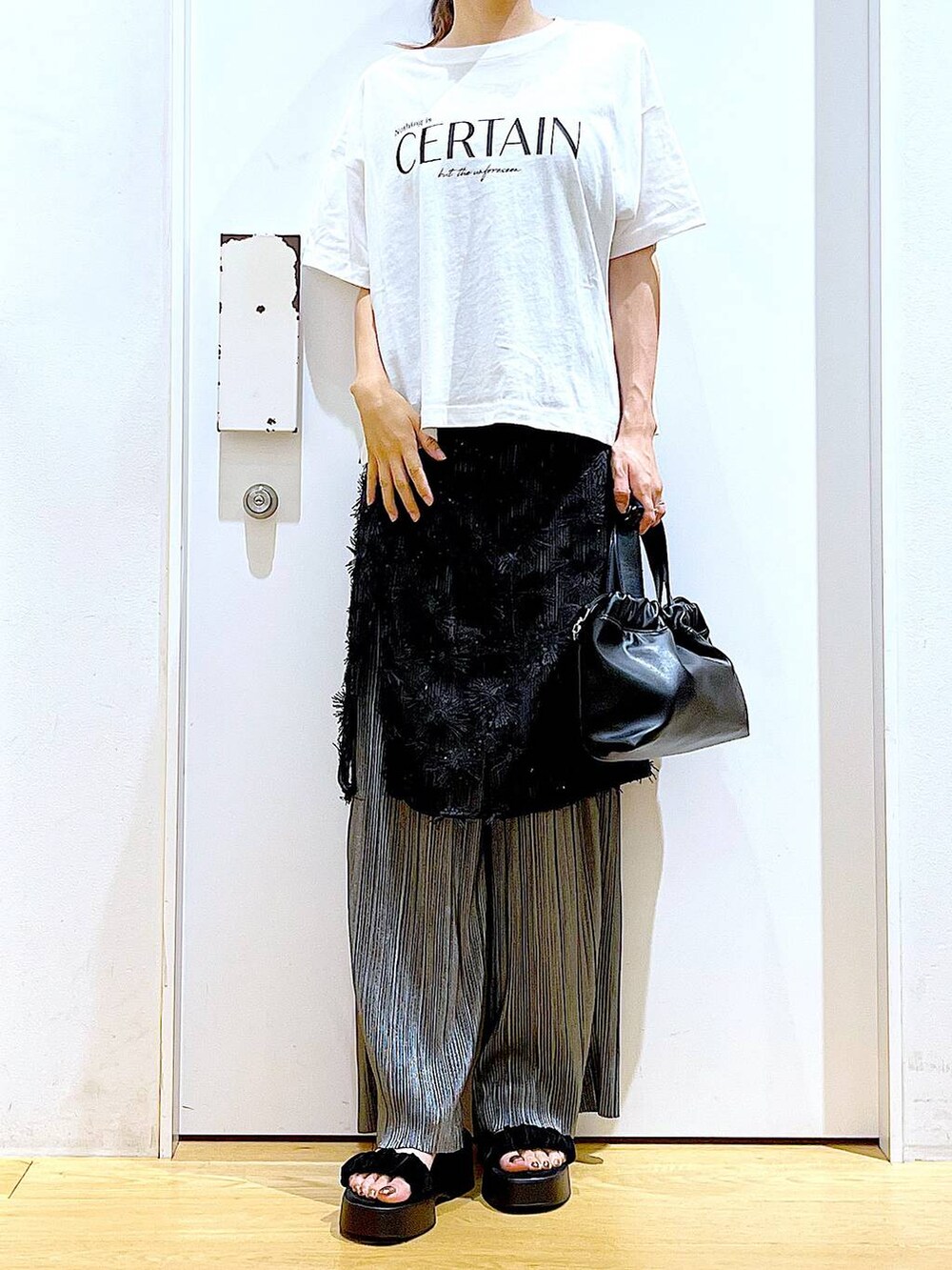 ブラック系のサンダル、ブラック系のショルダーバッグ、ブラック系のスカートを着用したレディースの秋コーディネートの6枚目の写真