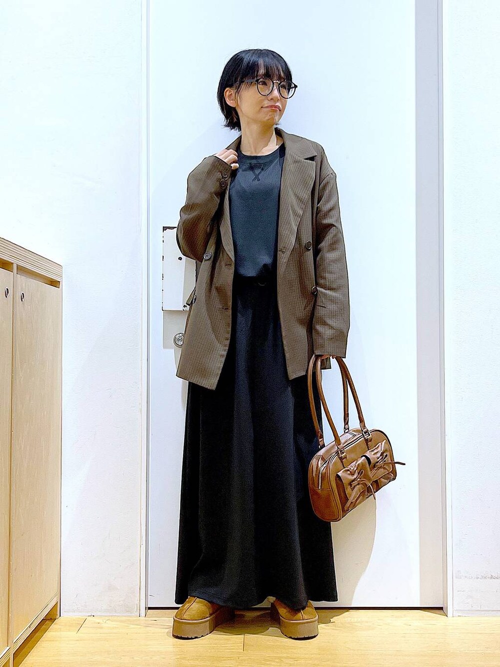 ベージュ系のスリッポン、ブラウン系のハンドバッグ、ブラウン系のテーラードジャケットを着用したレディースの秋コーディネートの2枚目の写真