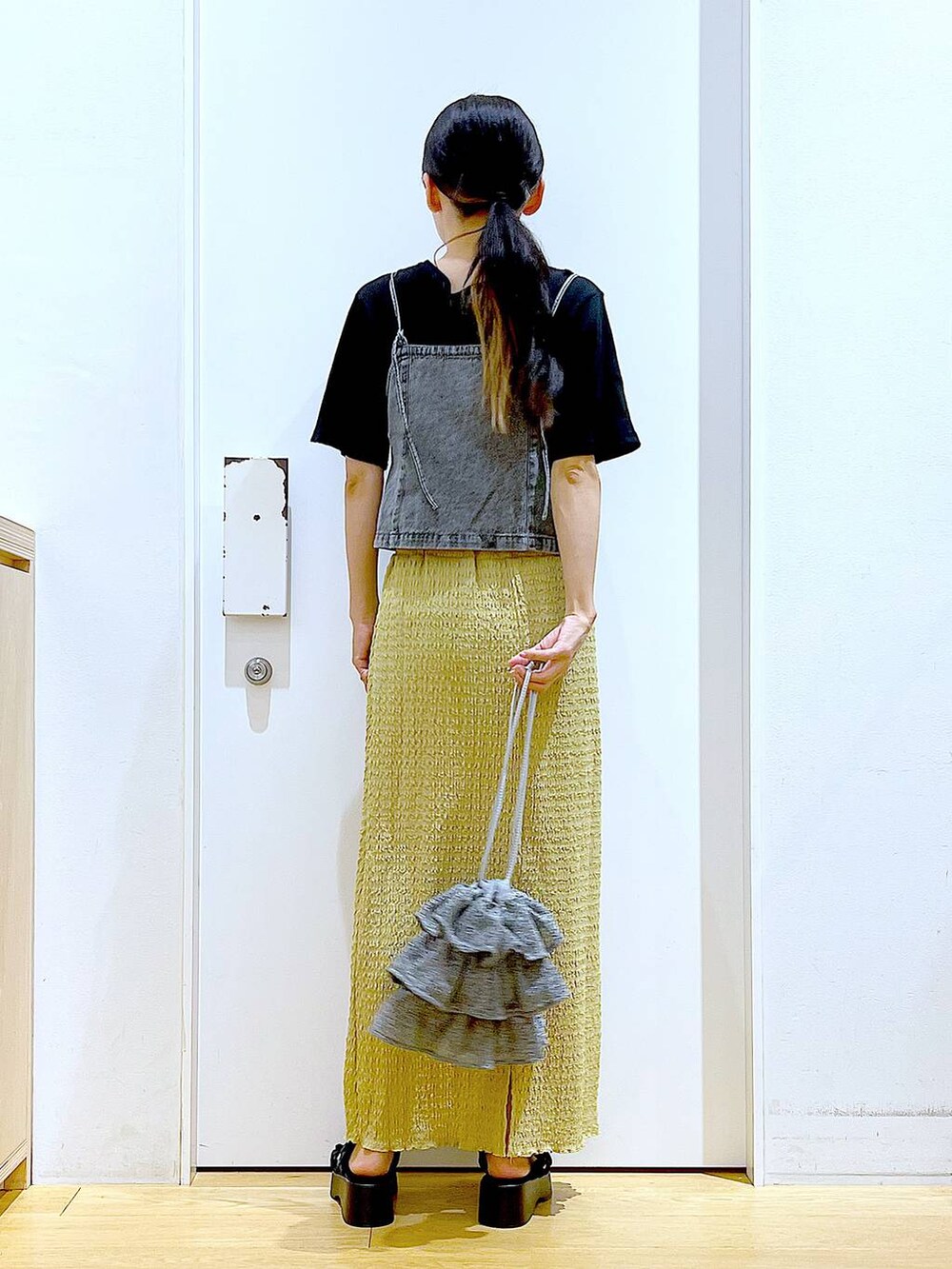 シルバー系のショルダーバッグ、グリーン系のスカート、ブラック系のTシャツ/カットソーを着用したレディースの夏コーディネートの5枚目の写真