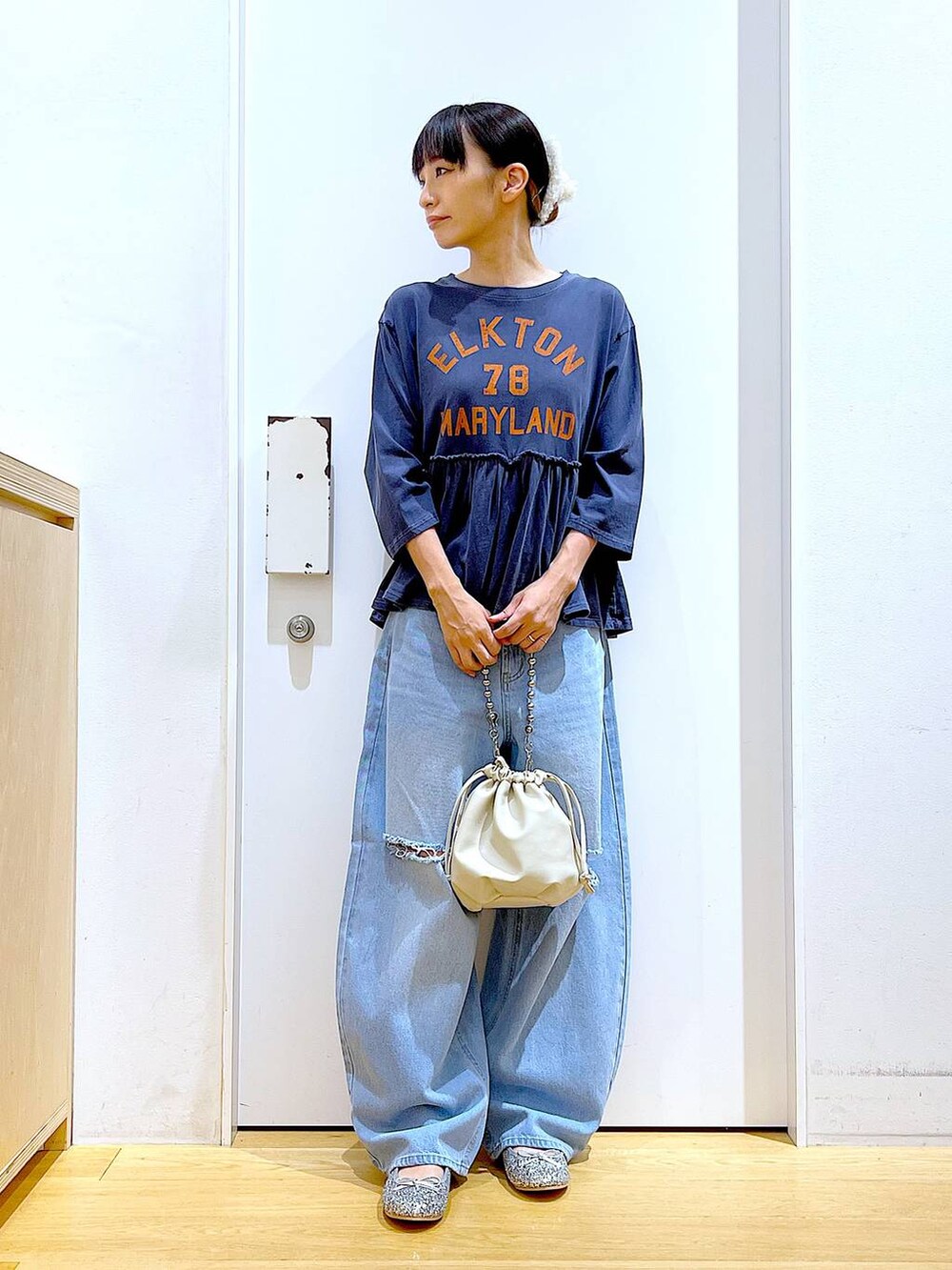 ブラック系のショルダーバッグ、ブルー系のデニムパンツ、シルバー系のパンプスを着用したレディースの秋コーディネートの2枚目の写真