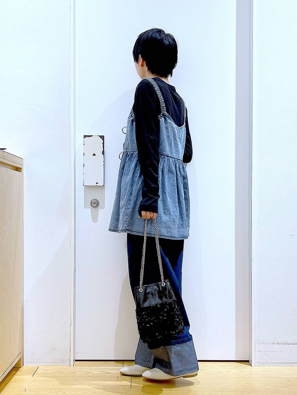 ホワイト系のパンプス、ブルー系のデニムパンツ、ブラック系のショルダーバッグを着用したレディースの春コーディネートの3枚目の写真