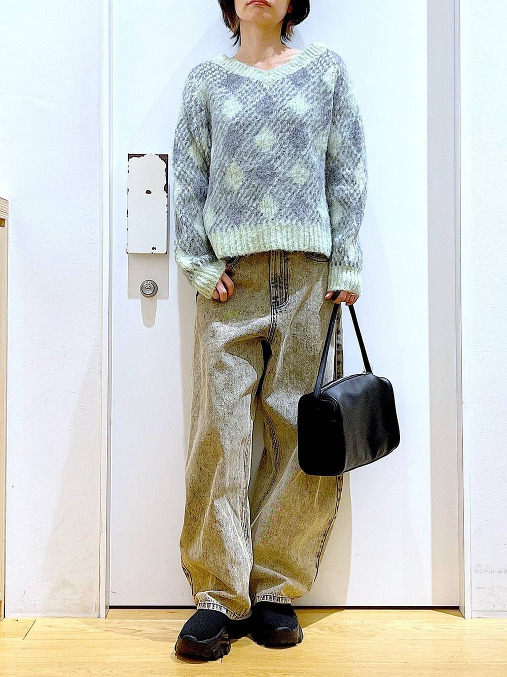 ブラック系のショルダーバッグ、ブラック系のブーツ、ベージュ系のデニムパンツを着用したレディースの冬コーディネートの6枚目の写真