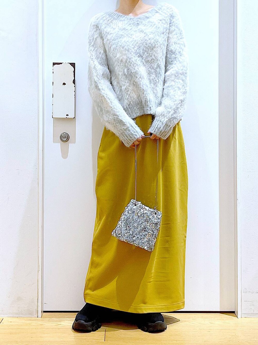 ブラック系のブーツ、イエロー系のスカート、その他のショルダーバッグを着用したレディースの冬コーディネートの6枚目の写真