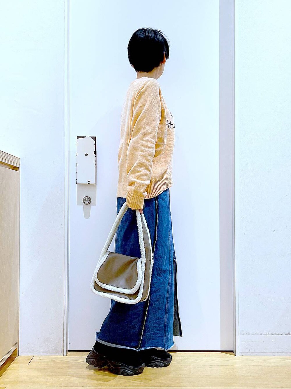 ブルー系のデニムスカート、ベージュ系のショルダーバッグ、ブラック系のブーツを着用したレディースの冬コーディネートの4枚目の写真