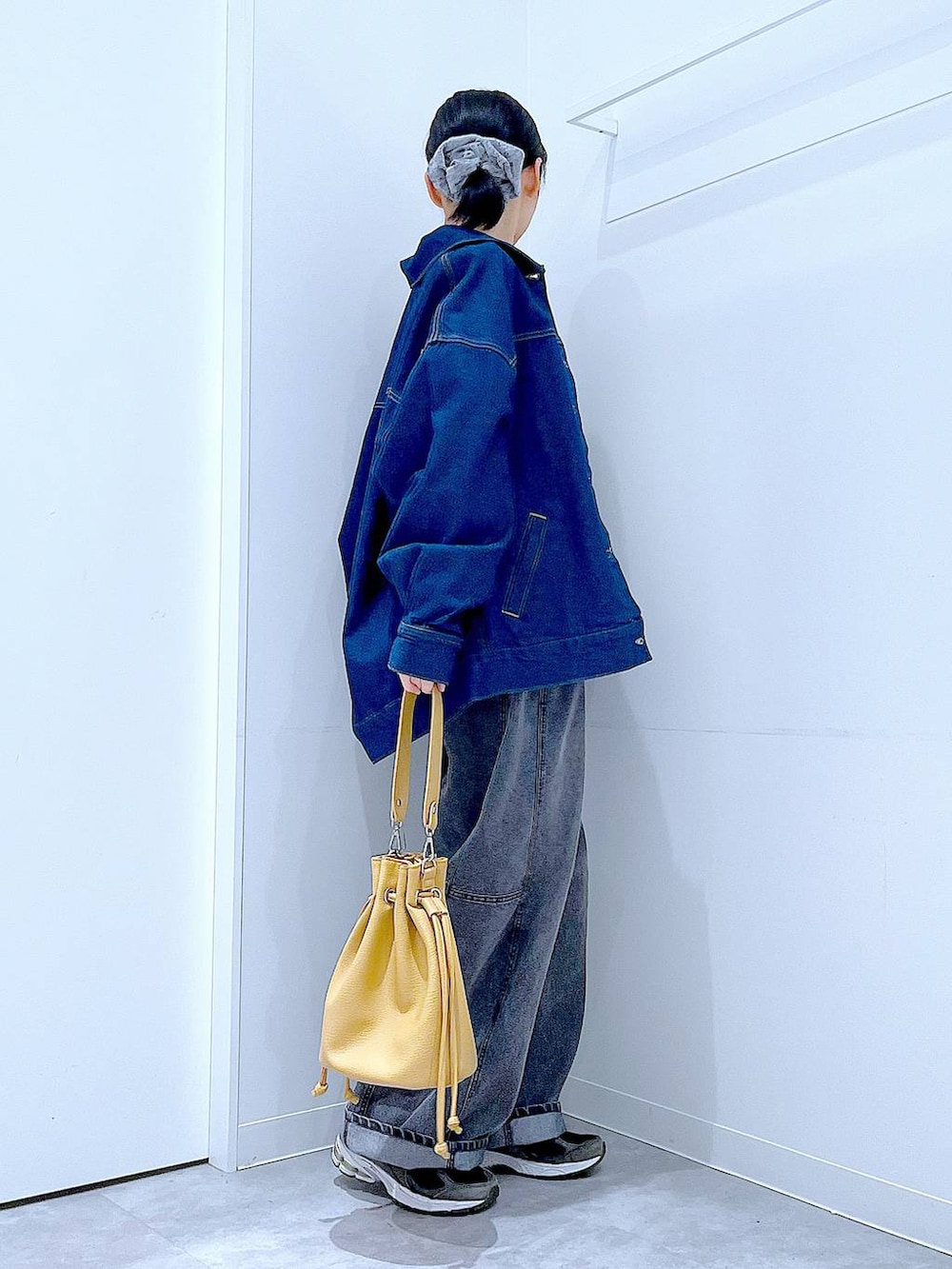 ブルー系のデニムジャケット、ブラック系のデニムパンツ、ブラウン系のショルダーバッグを着用したレディースの春コーディネートの4枚目の写真