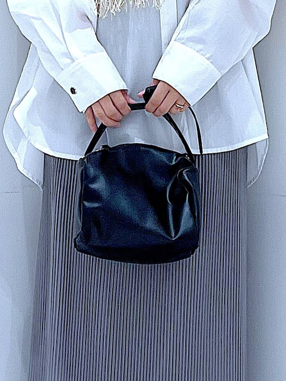 ブラック系のショルダーバッグ、ベージュ系のベスト、グレー系のスカートを着用したレディースの春コーディネートの9枚目の写真