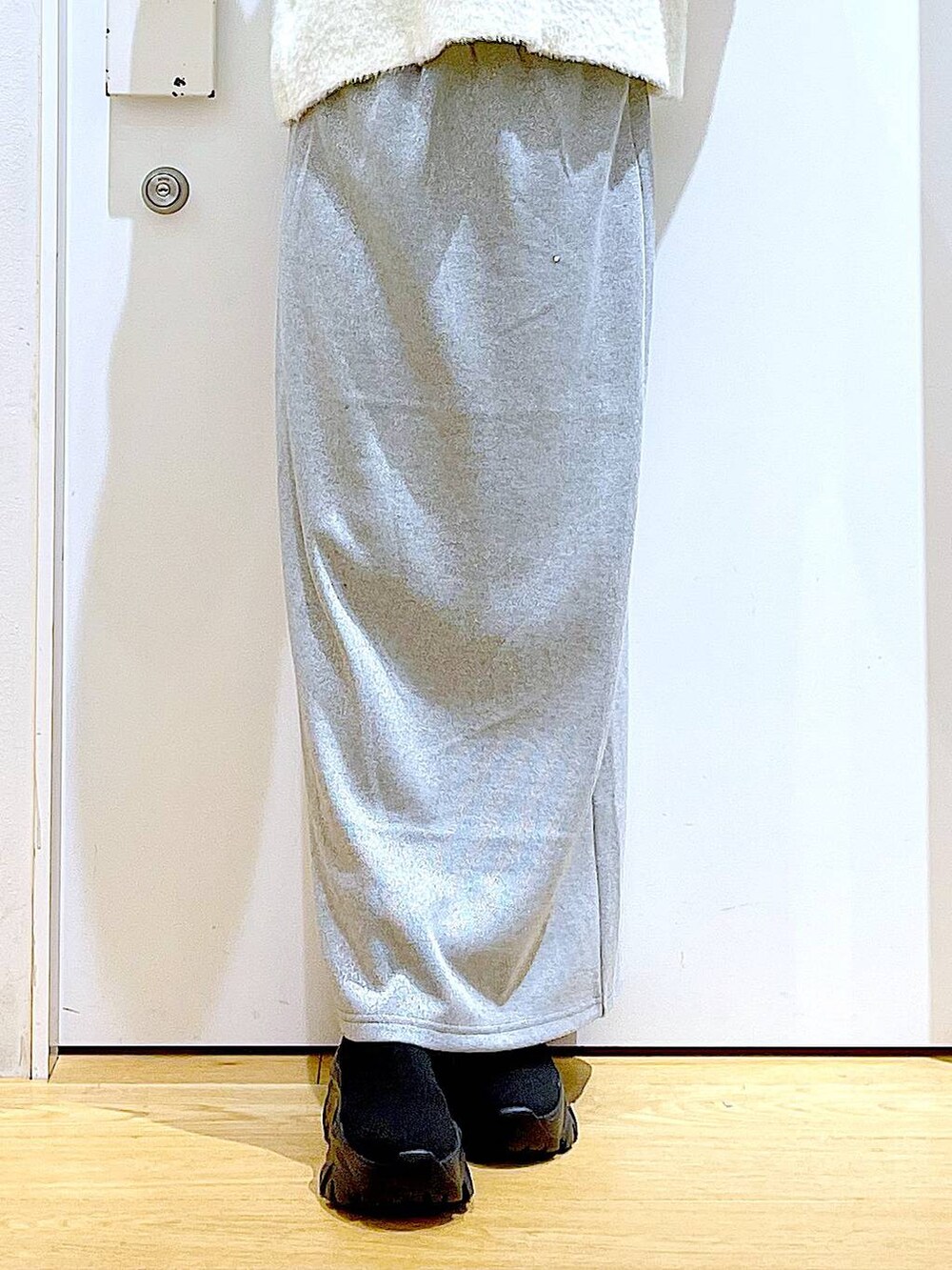 ブラック系のハンドバッグ、ブラック系のブーツ、グレー系のスカートを着用したレディースの冬コーディネートの8枚目の写真