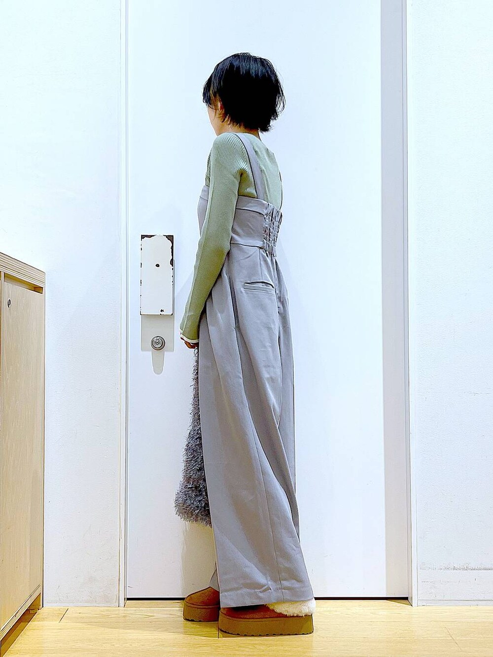 グリーン系のニット/セーター、グレー系のサロペット/オーバーオール、グレー系のショルダーバッグを着用したレディースの秋コーディネートの3枚目の写真