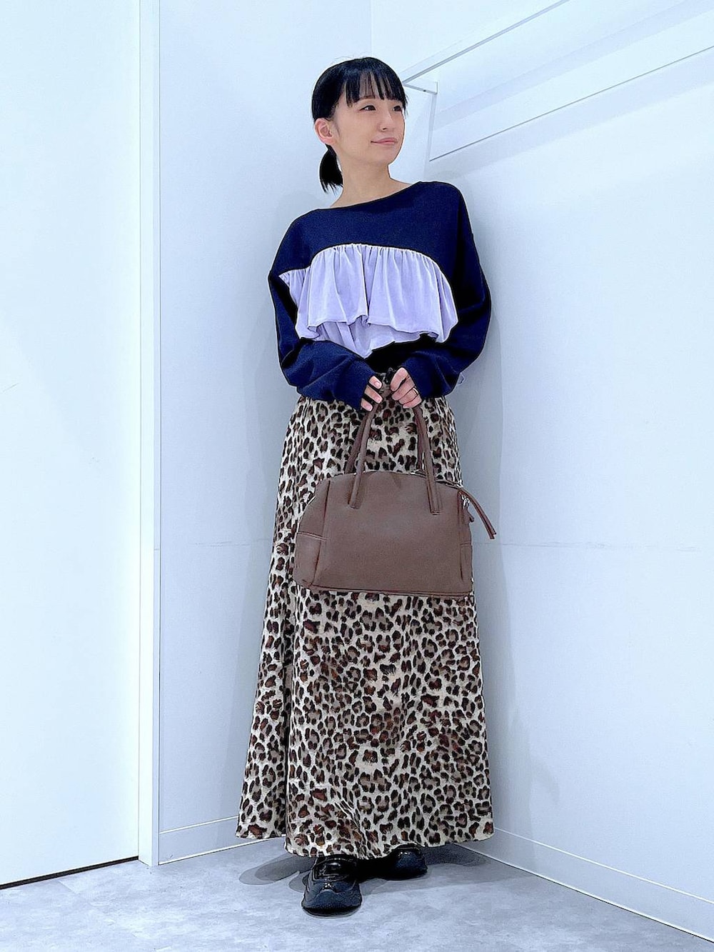 ブラック系のローファー、ブラウン系のボストンバッグ、ブラウン系のスカートを着用したレディースの秋コーディネートの2枚目の写真