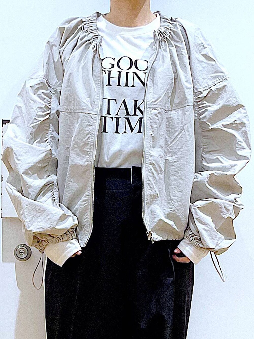 ブラック系のスラックス、ブラック系のスニーカー、ブラック系のショルダーバッグを着用したレディースの春コーディネートの7枚目の写真