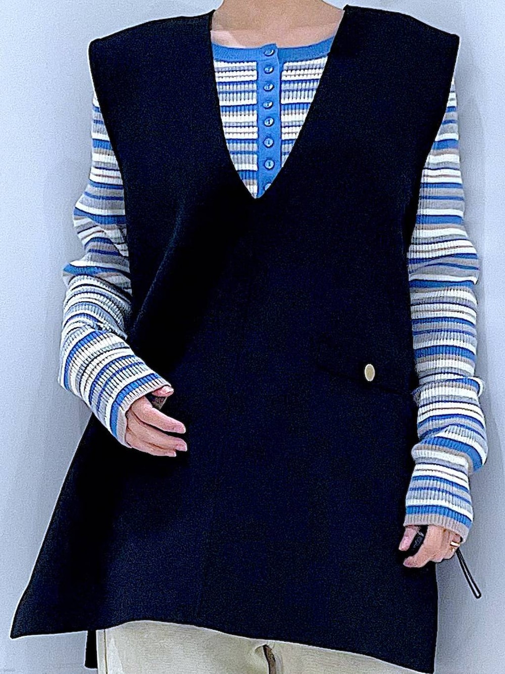 ブルー系のニット/セーター、ブラック系のベスト、ベージュ系のデニムパンツを着用したレディースの冬コーディネートの7枚目の写真