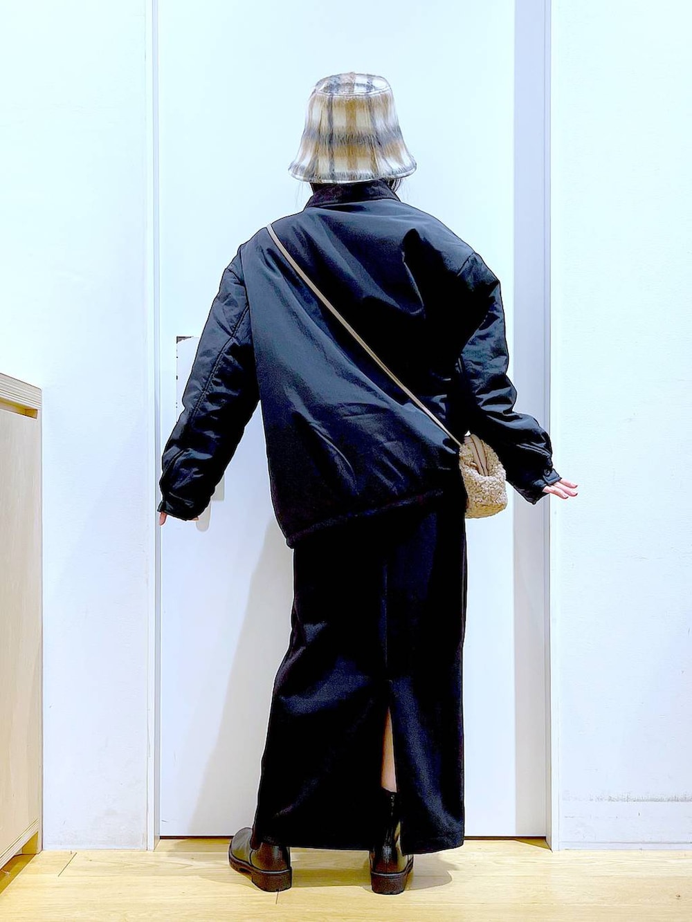 ブラック系のブルゾン、ブラック系のブーツ、ブラウン系のクラッチバッグを着用したレディースの冬コーディネートの5枚目の写真