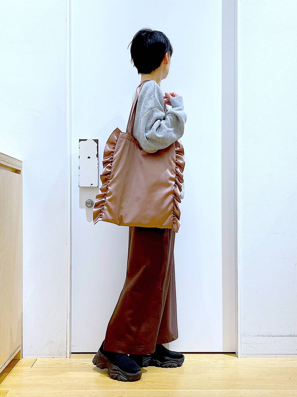 ブラック系のブーツ、ピンク系のトートバッグ、ブラウン系のスカートを着用したレディースの冬コーディネートの4枚目の写真