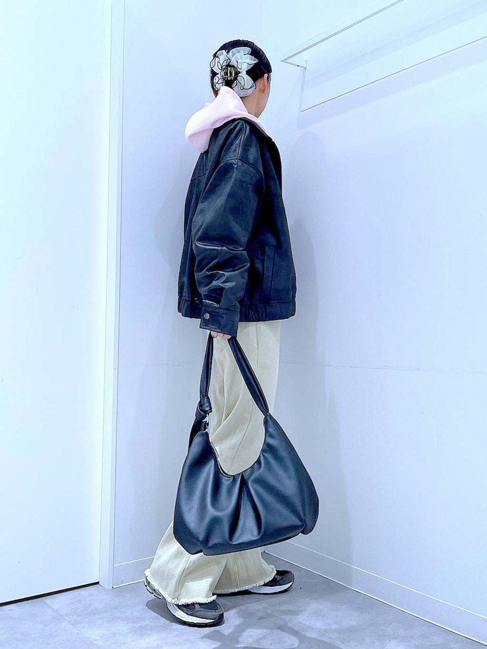 ブラック系のブルゾン、ベージュ系のデニムパンツ、ピンク系のパーカーを着用したレディースの冬コーディネートの4枚目の写真