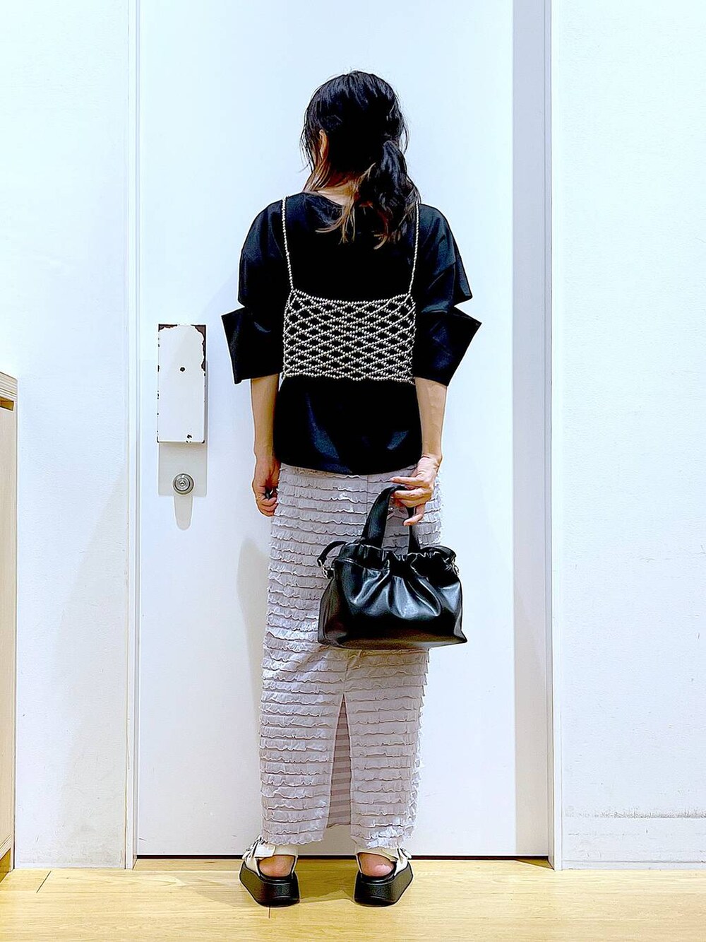 ホワイト系のサンダル、ブラック系のショルダーバッグ、シルバー系のベストを着用したレディースの夏コーディネートの5枚目の写真