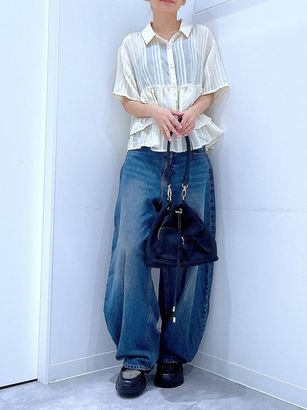 ブルー系のデニムパンツ、ブラック系のスニーカー、ブラック系のショルダーバッグを着用したレディースの春コーディネートの6枚目の写真