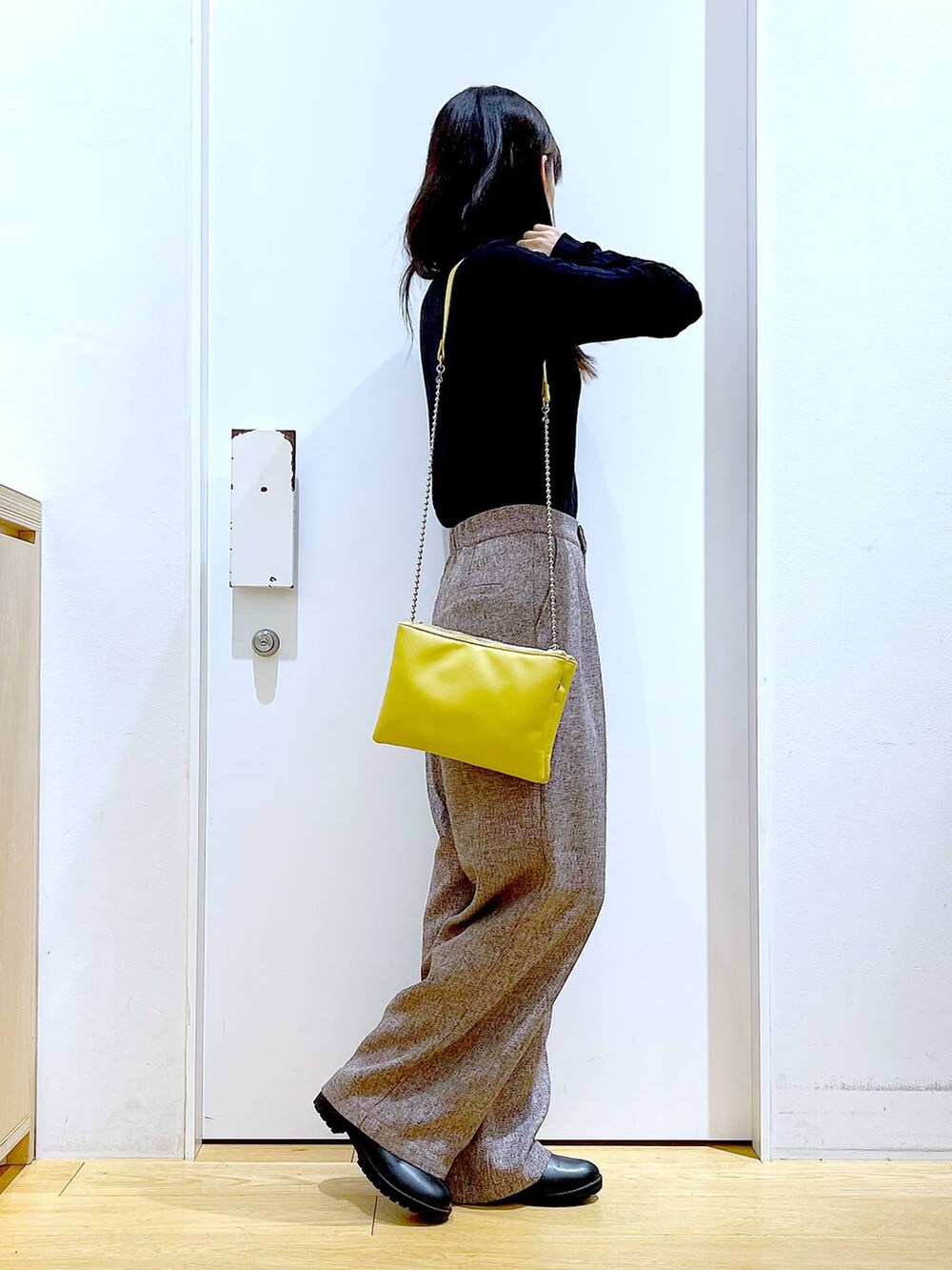 イエロー系のショルダーバッグ、ブラック系のブーツ、ブラウン系のその他パンツを着用したレディースの冬コーディネートの4枚目の写真