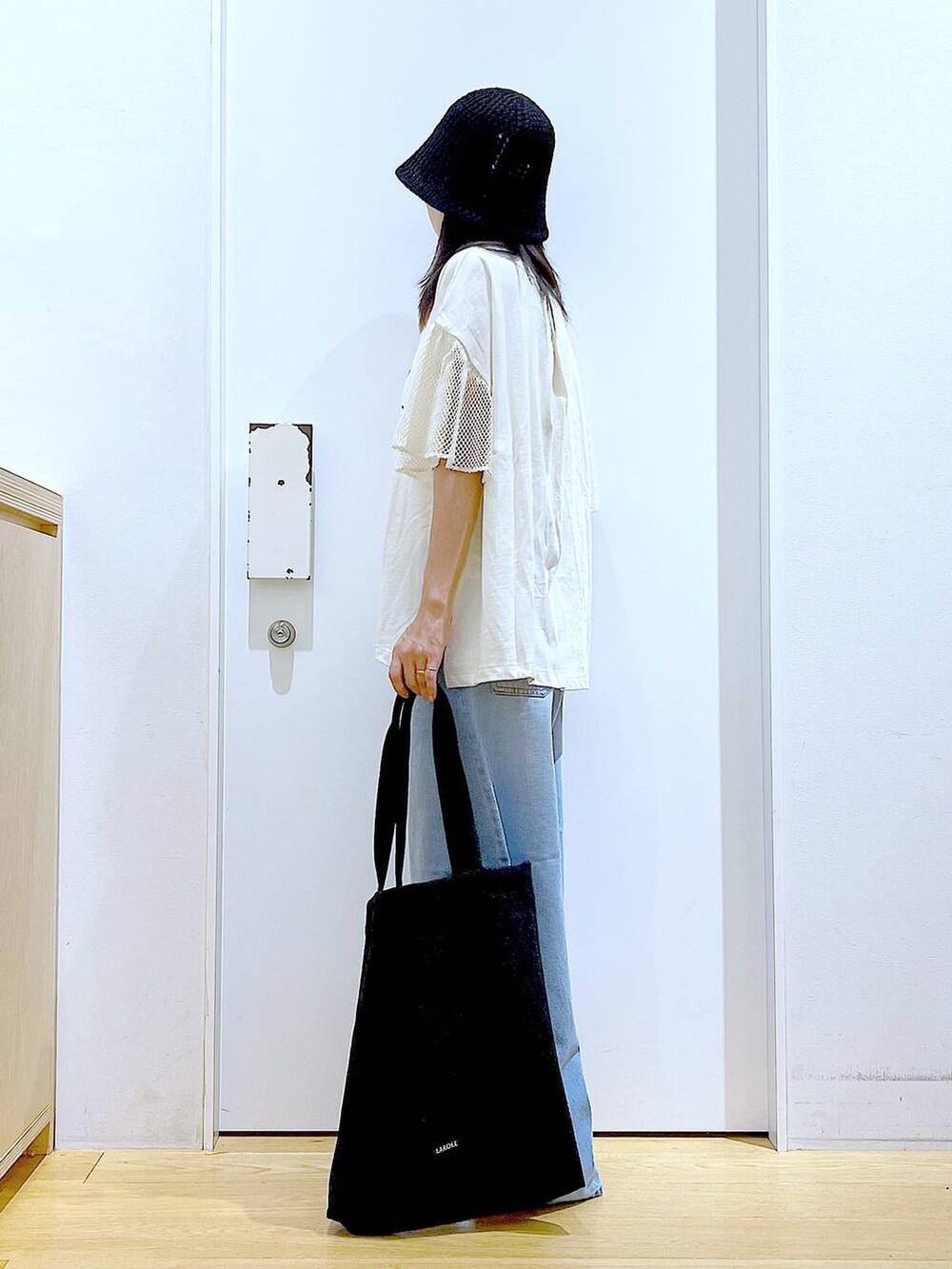 ブラック系のトートバッグ、ブルー系のデニムパンツ、シルバー系のパンプスを着用したレディースの夏コーディネートの3枚目の写真