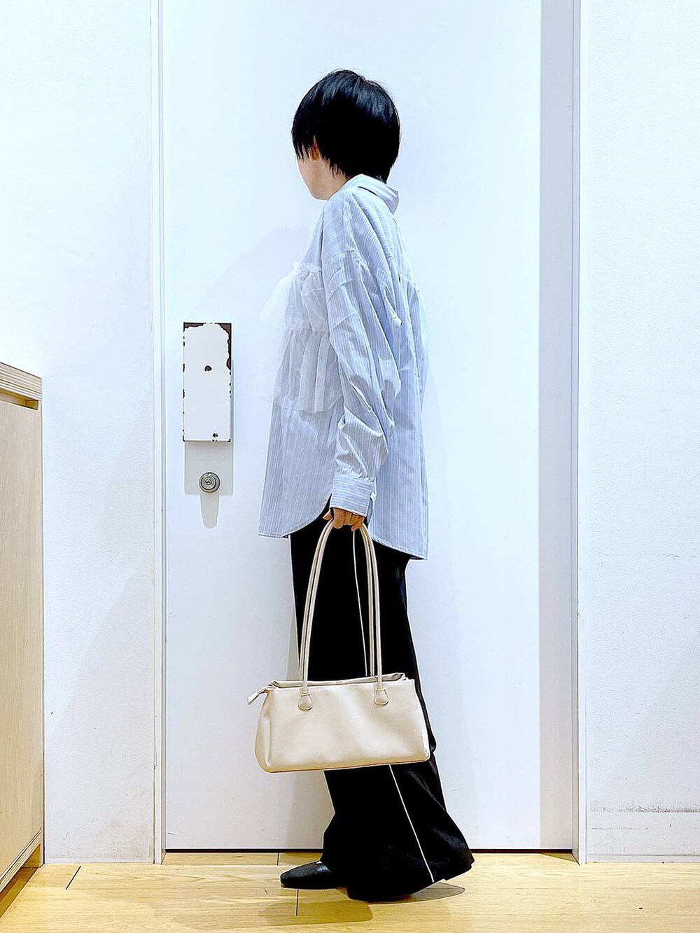 ブラック系のスラックス、ホワイト系のトートバッグ、ブラック系のパンプスを着用したレディースの春コーディネートの3枚目の写真