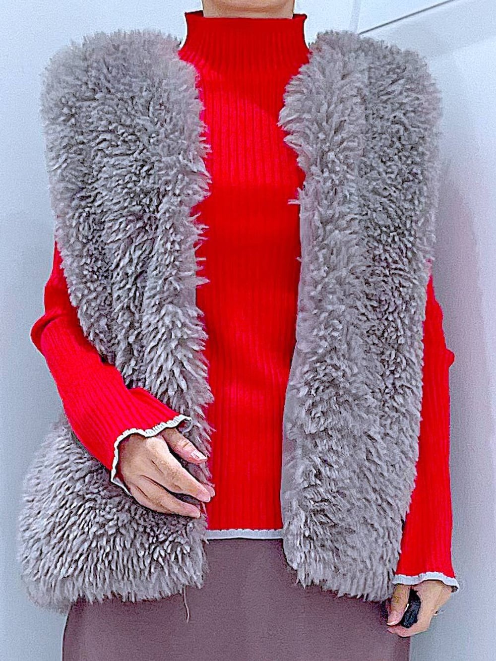 グレー系のベスト、レッド系のニット/セーター、ブラック系のブーツを着用したレディースの冬コーディネートの7枚目の写真