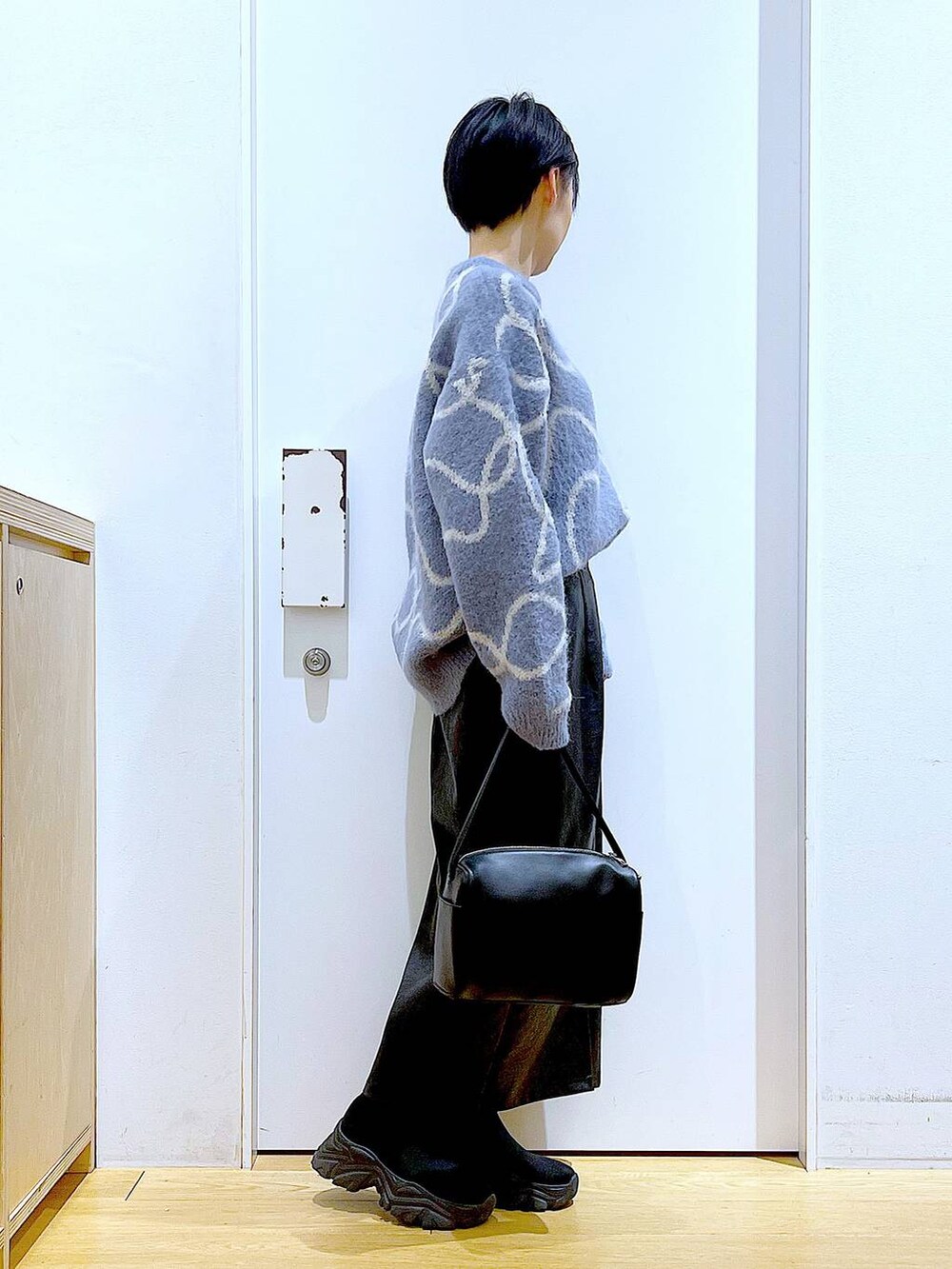 ブラック系のスカート、ブラック系のショルダーバッグ、ブラック系のブーツを着用したレディースの冬コーディネートの4枚目の写真