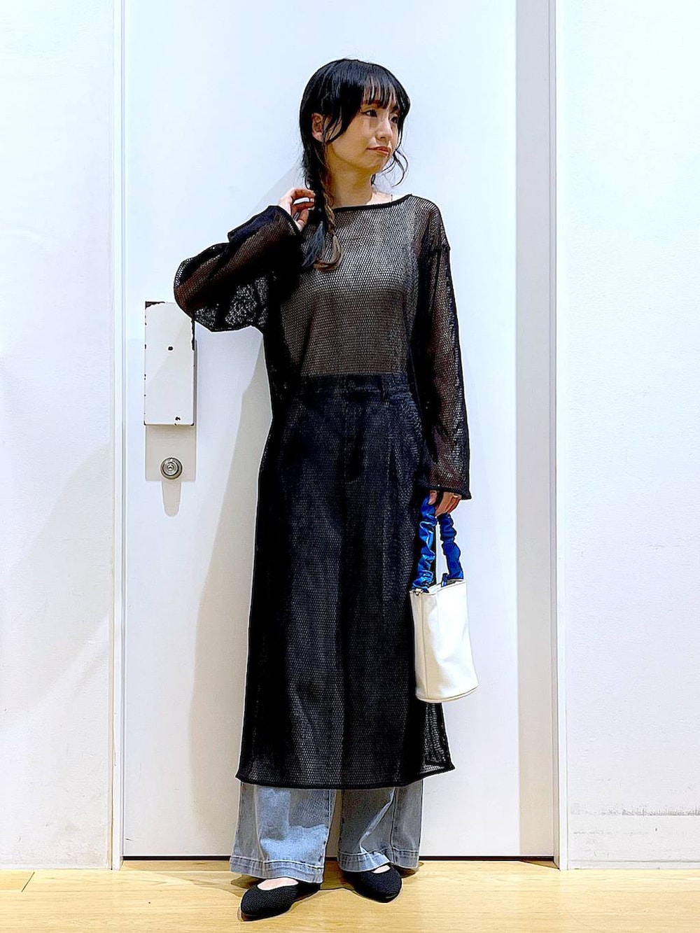 ブルー系のショルダーバッグ、ブラック系のパンプス、ブルー系のデニムパンツを着用したレディースの春コーディネートの2枚目の写真