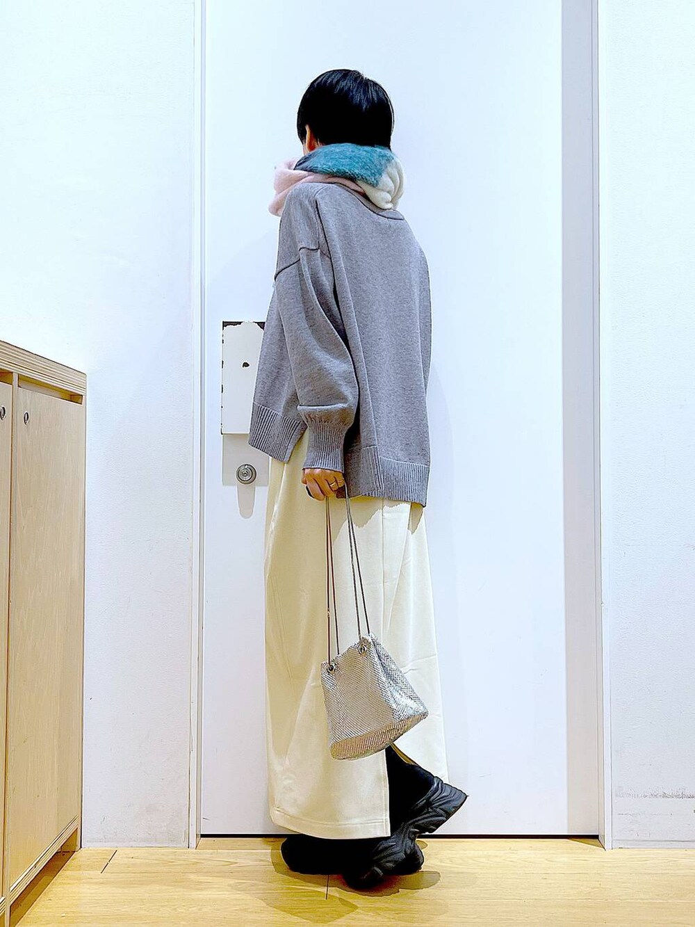 ブラック系のブーツ、ホワイト系のスカート、グレー系のニット/セーターを着用したレディースの冬コーディネートの3枚目の写真