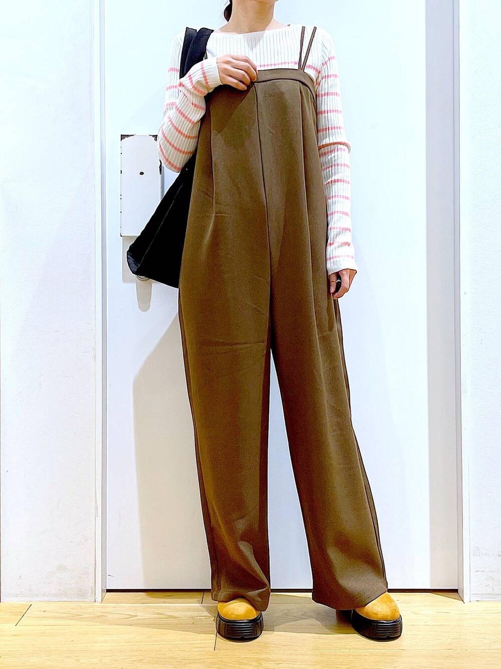 ピンク系のニット/セーター、ブラック系のショルダーバッグ、ベージュ系のブーツを着用したレディースの冬コーディネートの6枚目の写真