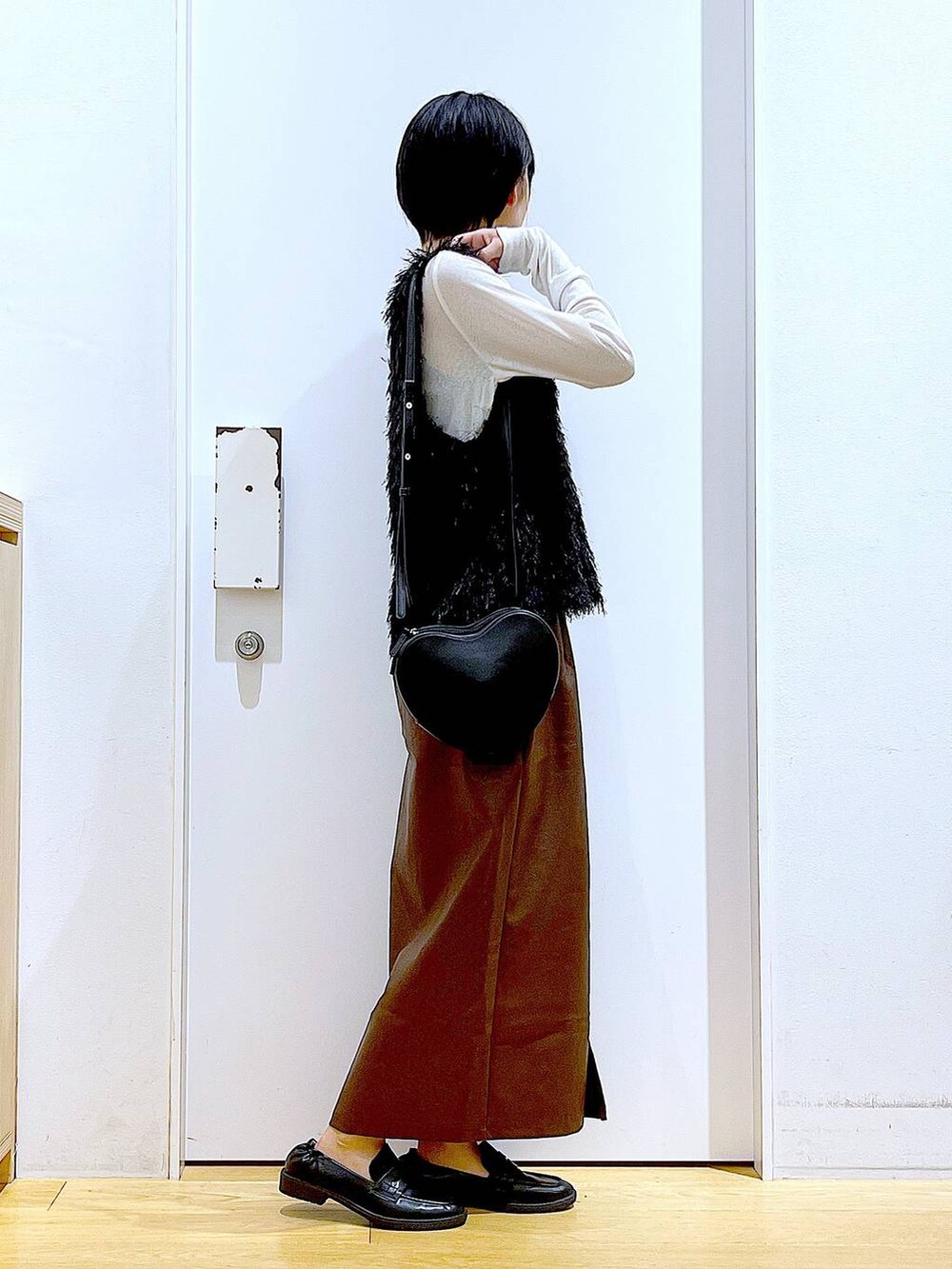 ブラウン系のスカート、ブラック系のショルダーバッグ、ホワイト系のTシャツ/カットソーを着用したレディースの秋コーディネートの4枚目の写真