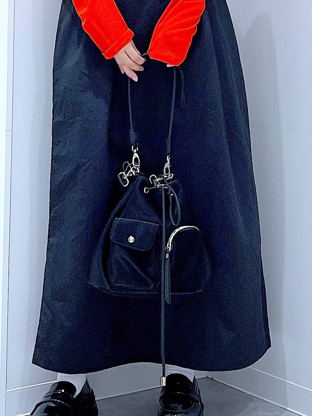 オレンジ系のTシャツ/カットソー、ブラック系のローファー、ブラック系のショルダーバッグを着用したレディースの秋コーディネートの9枚目の写真