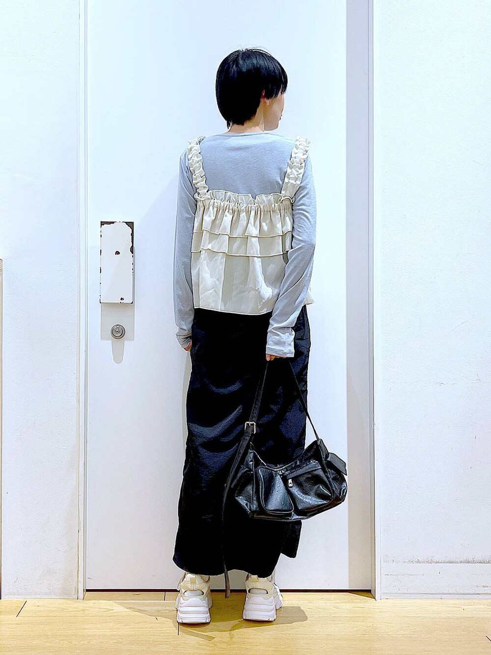 ブラック系のスカート、ブラック系のショルダーバッグ、ホワイト系のスニーカーを着用したレディースの春コーディネートの5枚目の写真