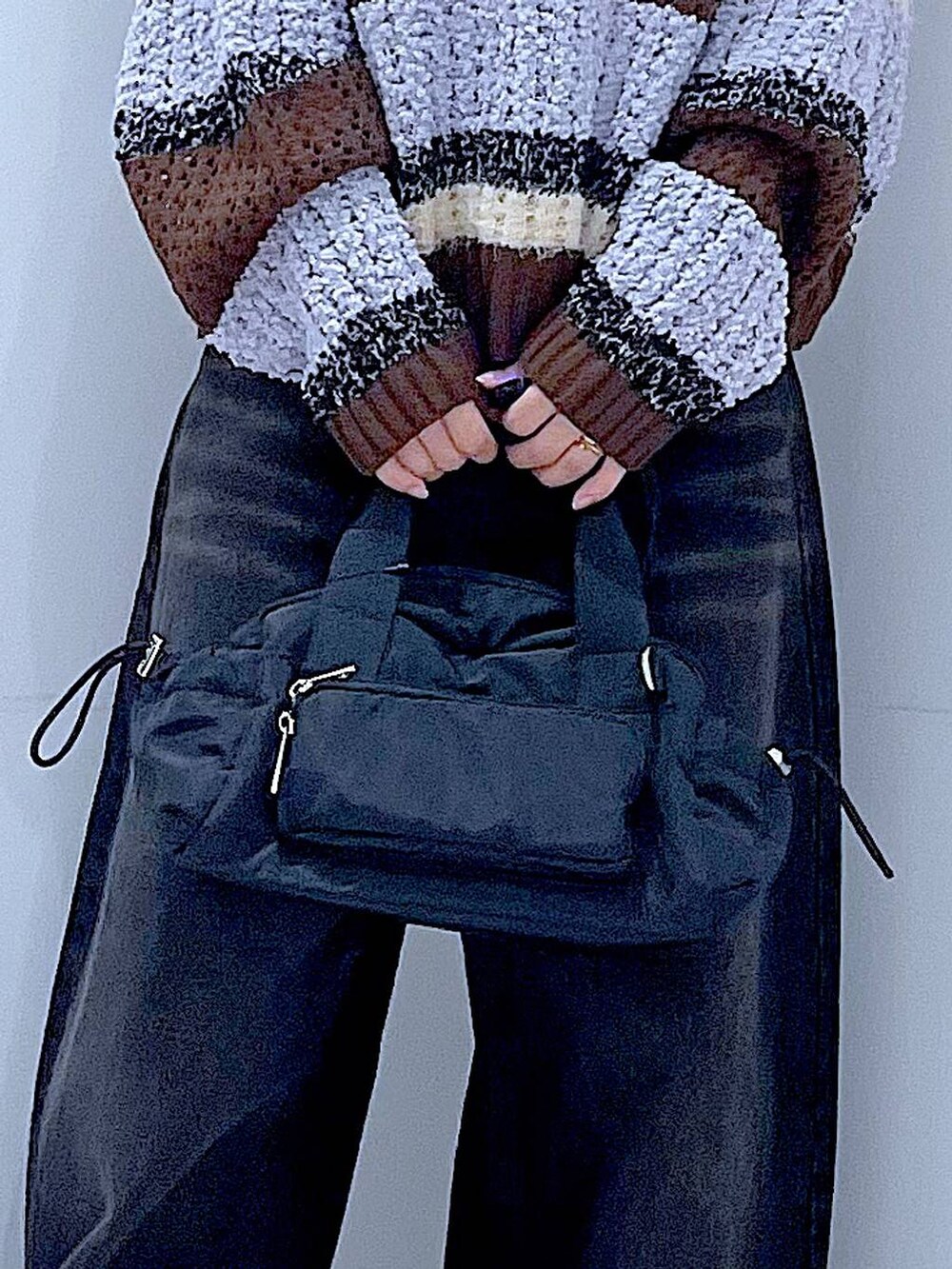 ブラック系のデニムパンツ、ブラック系のショルダーバッグ、ブラウン系のニット/セーターを着用したレディースの秋コーディネートの9枚目の写真