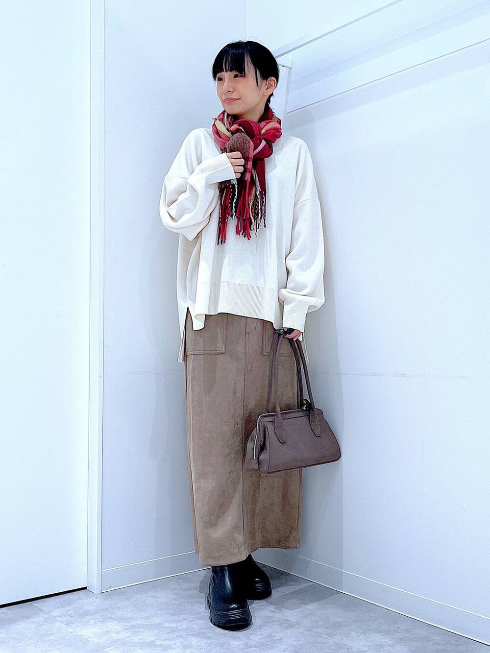 ブラック系のブーツ、ベージュ系のニット/セーター、ブラウン系のスカートを着用したレディースの秋コーディネートの2枚目の写真