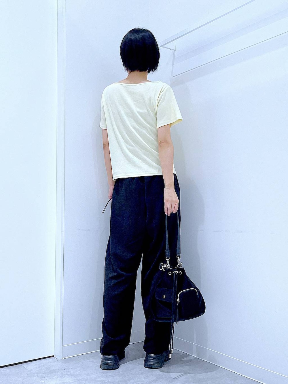 ブラック系のスニーカー、ブラック系のショルダーバッグ、イエロー系のTシャツ/カットソーを着用したレディースの夏コーディネートの5枚目の写真