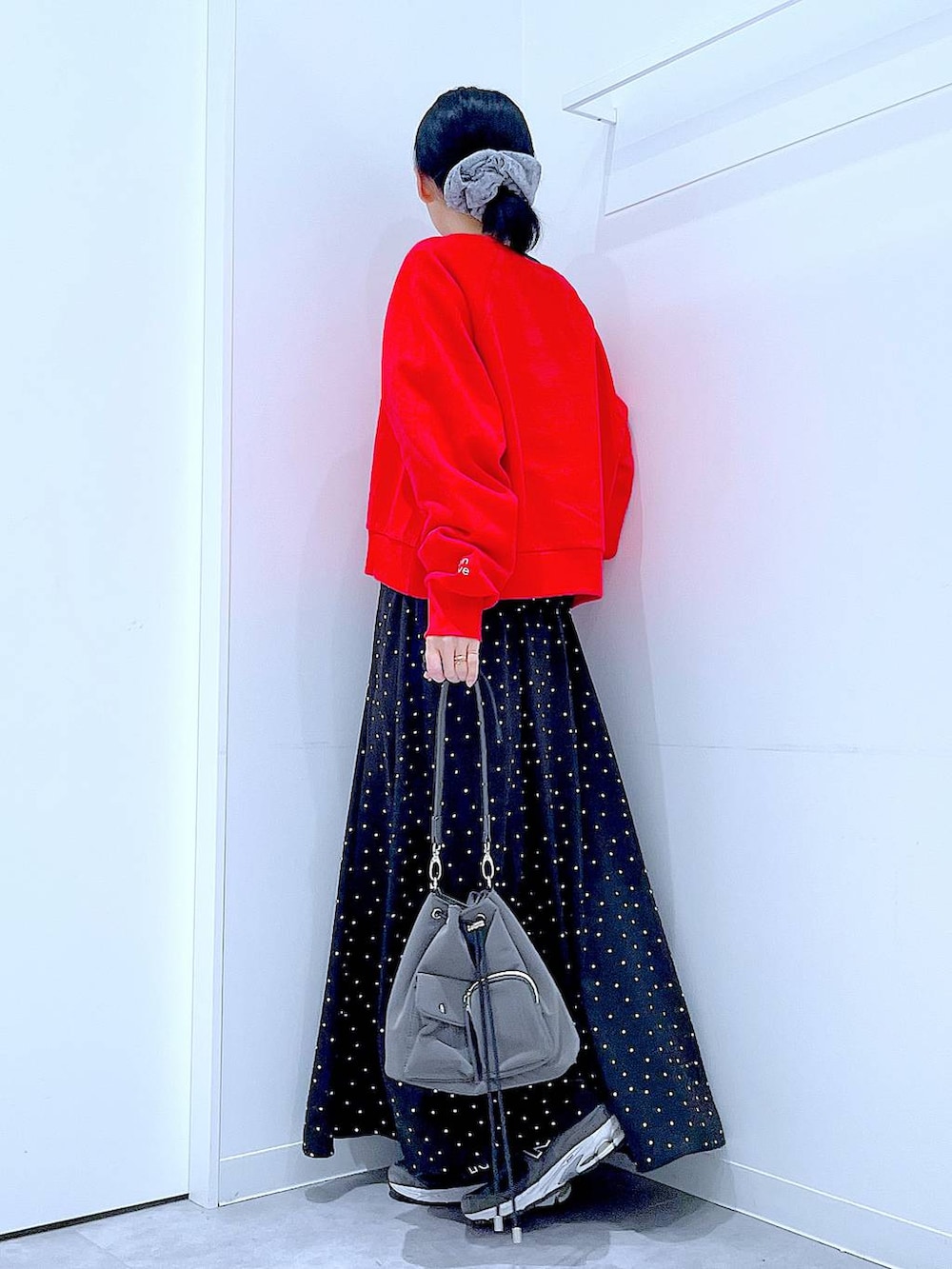 レッド系のスウェット、グレー系のシュシュを着用したレディースの春コーディネートの3枚目の写真