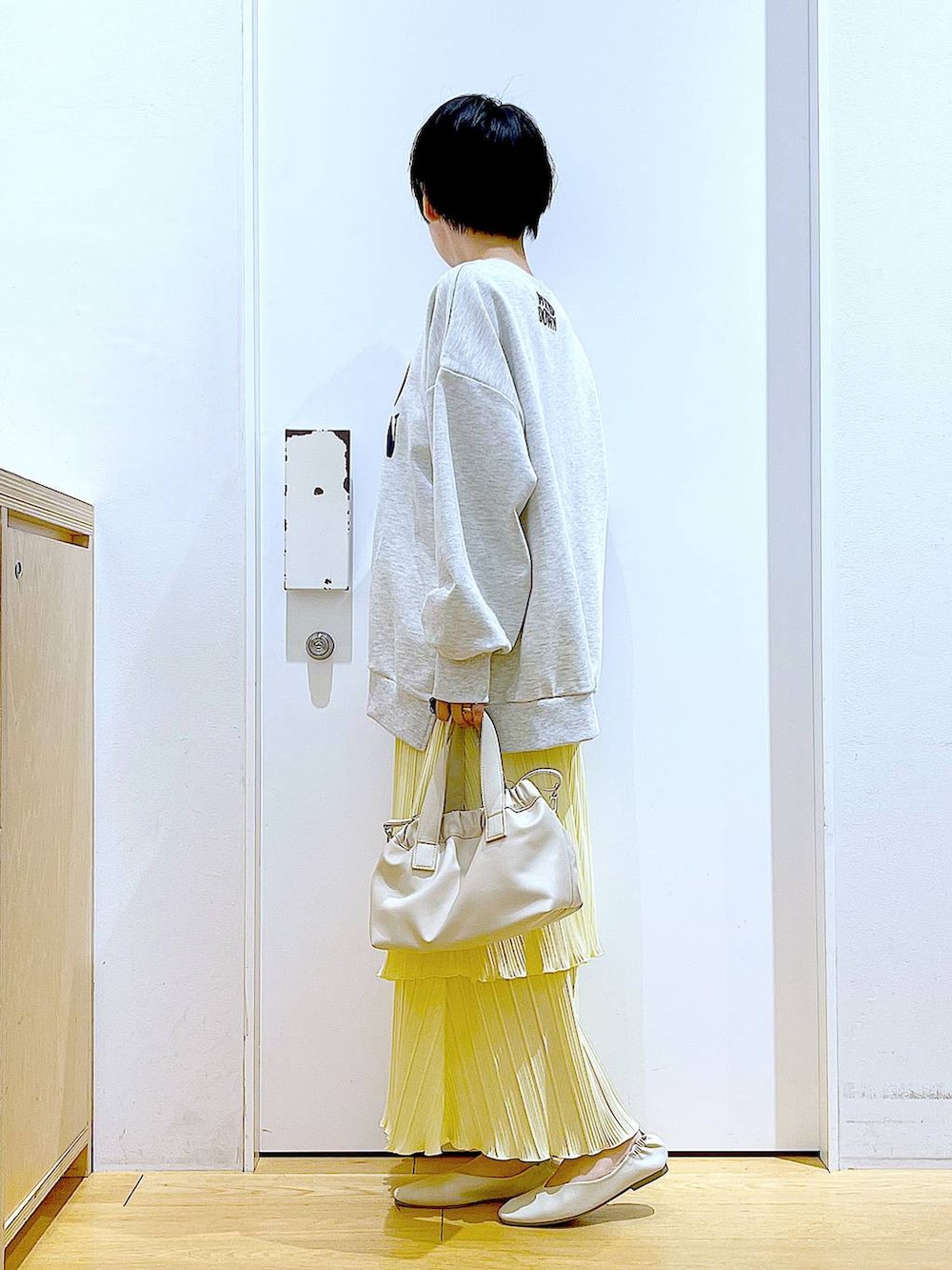 ホワイト系のショルダーバッグ、ホワイト系のパンプス、ベージュ系のスウェットを着用したレディースの冬コーディネートの3枚目の写真