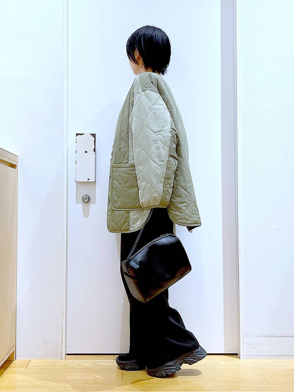 ブラック系のショルダーバッグ、ホワイト系のスウェット、ブラック系のブーツを着用したレディースの秋コーディネートの3枚目の写真