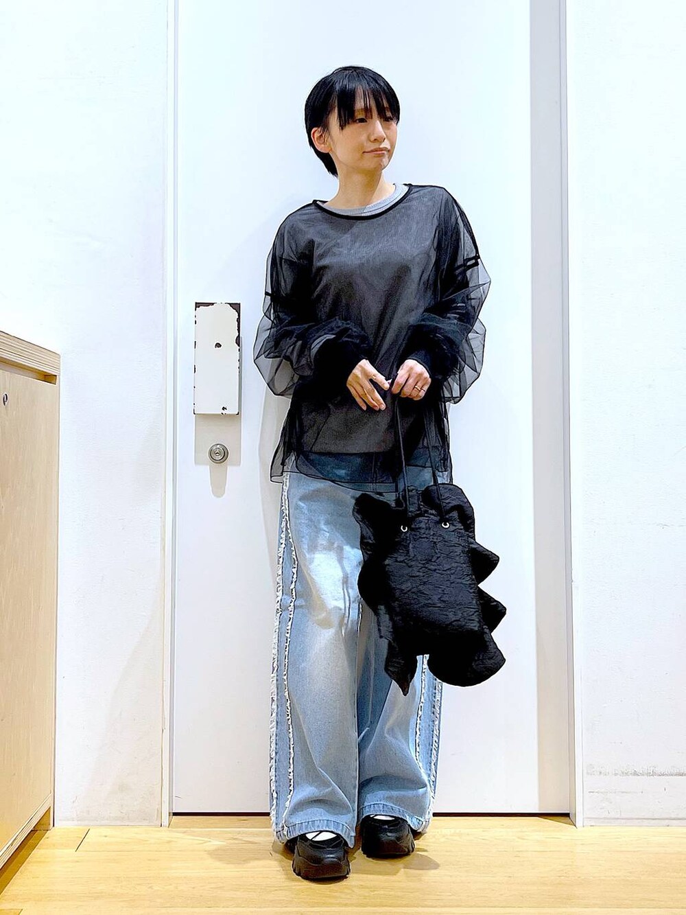 ブラック系のスニーカー、ブラック系のショルダーバッグ、ブルー系のデニムパンツを着用したレディースの春コーディネートの2枚目の写真