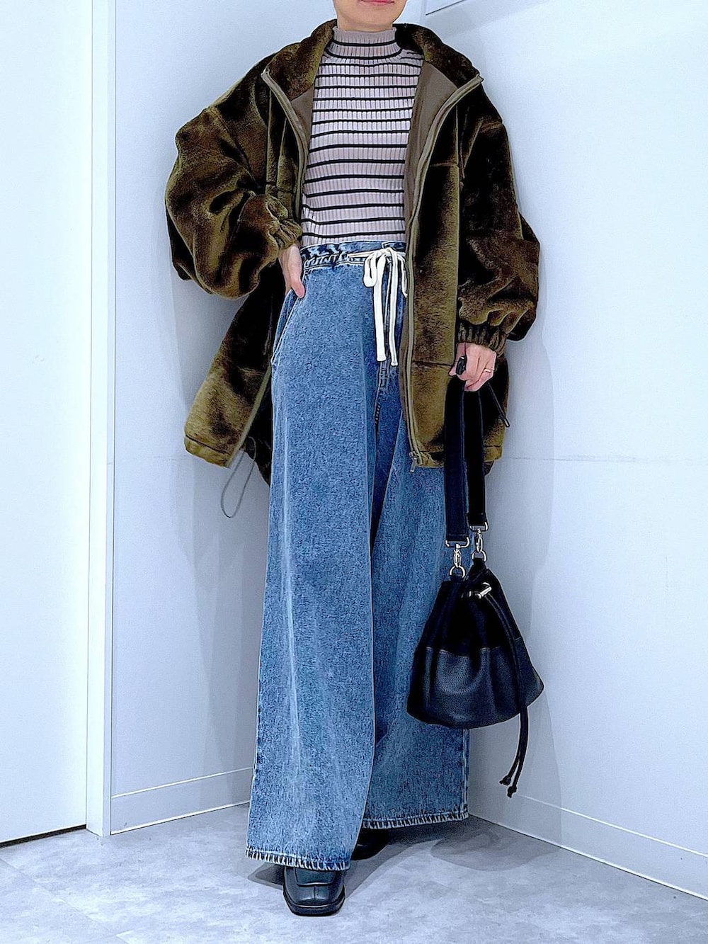 グリーン系のブルゾン、その他のニット/セーター、ブルー系のデニムパンツを着用したレディースの冬コーディネートの6枚目の写真