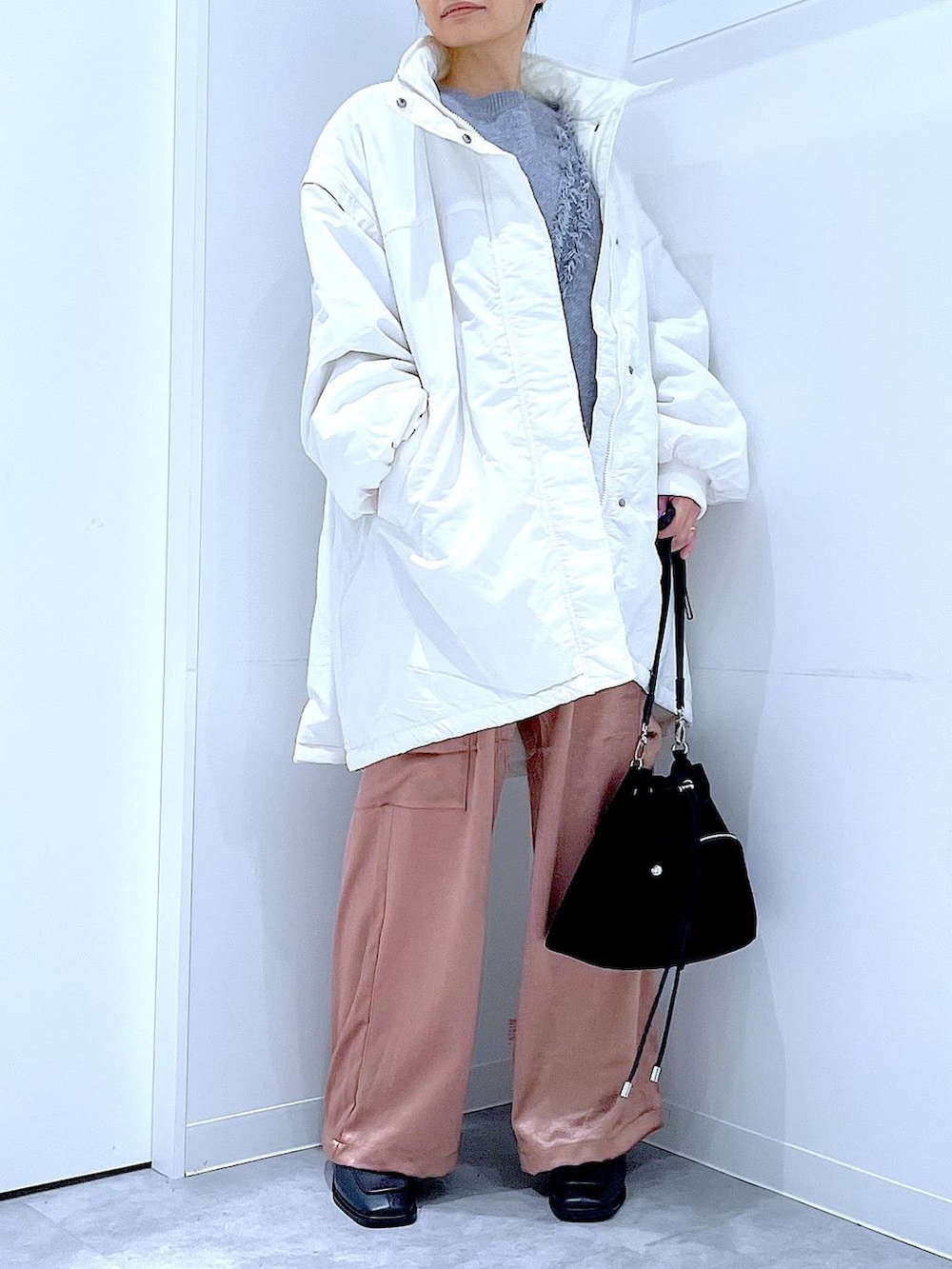 ホワイト系のブルゾン、ブラック系のショルダーバッグ、ブラック系のブーツを着用したレディースの冬コーディネートの6枚目の写真