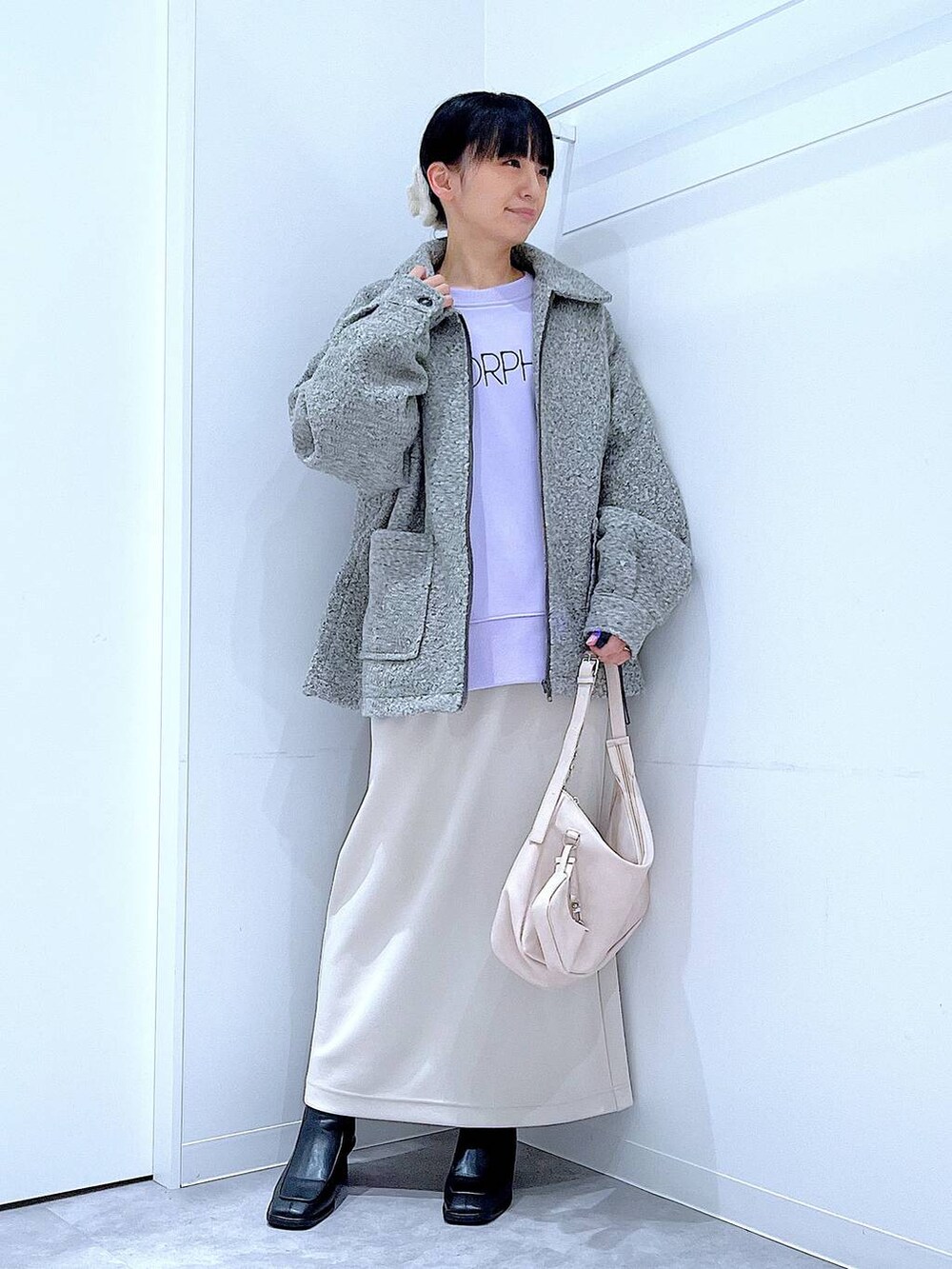 ベージュ系のスカート、グレー系のブルゾン、ブラック系のブーツを着用したレディースの秋コーディネートの2枚目の写真