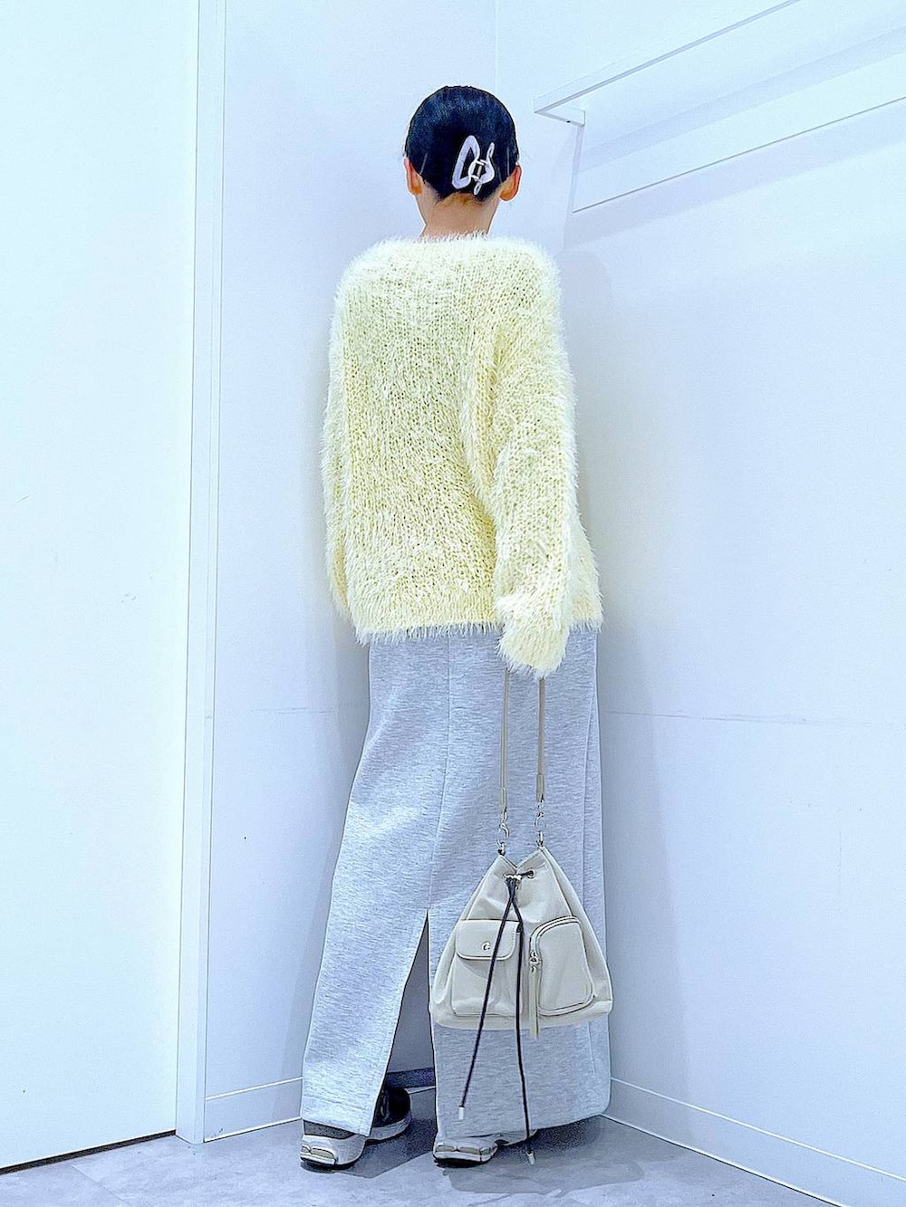 イエロー系のニット/セーター、グレー系のスカート、パープル系のバレッタ/ヘアクリップを着用したレディースの冬コーディネートの5枚目の写真