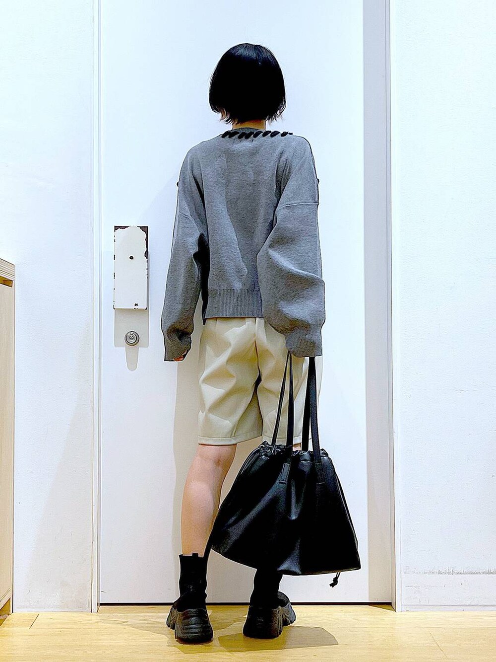 ブラック系のトートバッグ、ブラック系のブーツ、グレー系のニット/セーターを着用したレディースの冬コーディネートの5枚目の写真