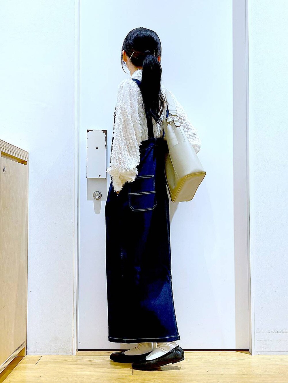 グレー系のショルダーバッグ、ブラック系のバレエシューズ、ブルー系のジャンパースカートを着用したレディースの春コーディネートの3枚目の写真