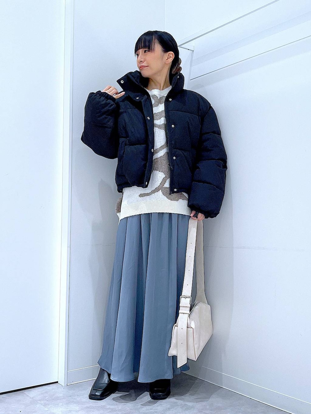 ブラック系のブルゾン、ブラック系のブーツ、ベージュ系のニット/セーターを着用したレディースの冬コーディネートの2枚目の写真