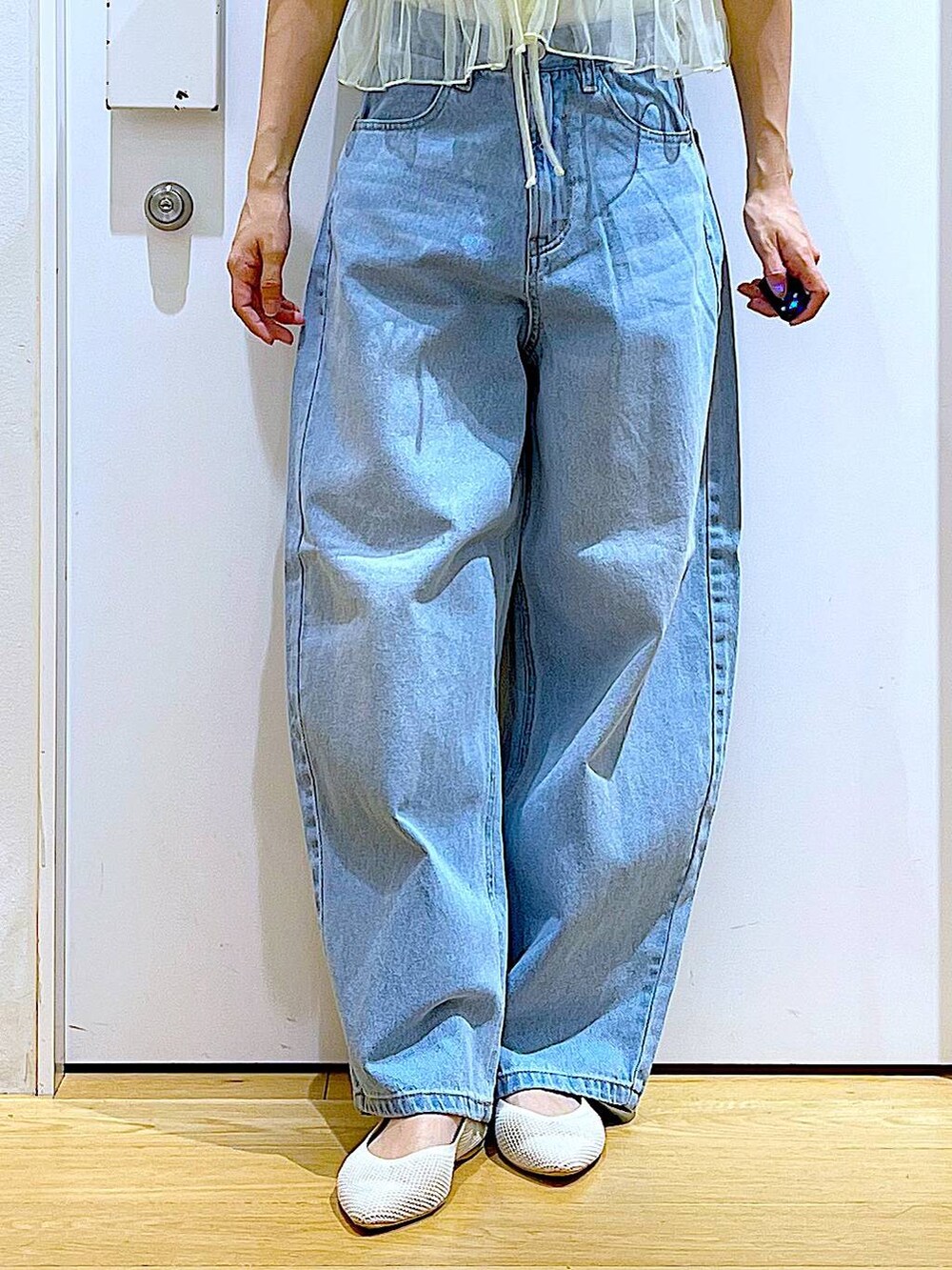 ブルー系のデニムパンツ、イエロー系のキャミソール、ホワイト系のトートバッグを着用したレディースの春コーディネートの8枚目の写真