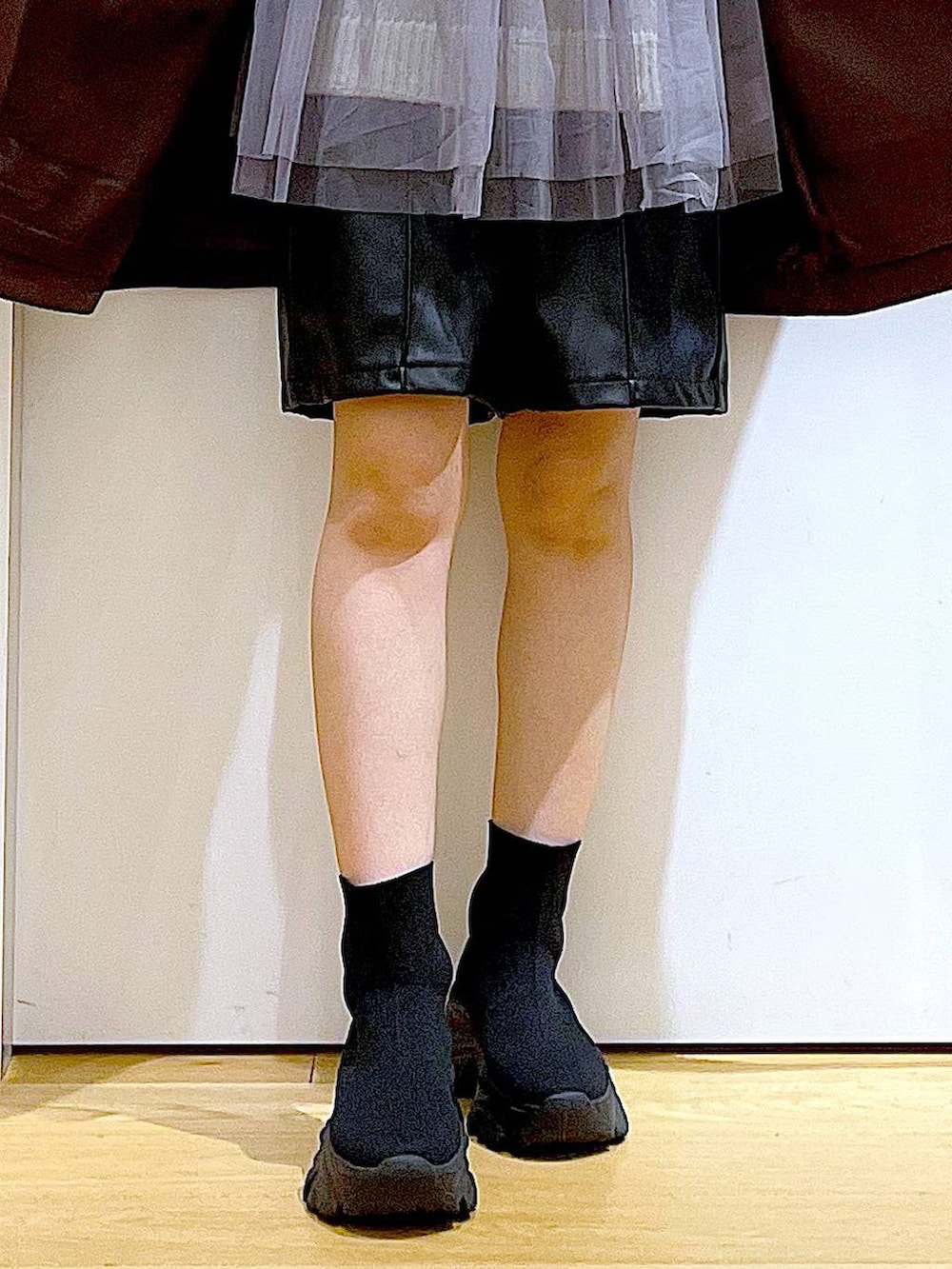 ブラウン系のステンカラーコート、ブラック系のハンドバッグ、ブラック系のブーツを着用したレディースの冬コーディネートの8枚目の写真