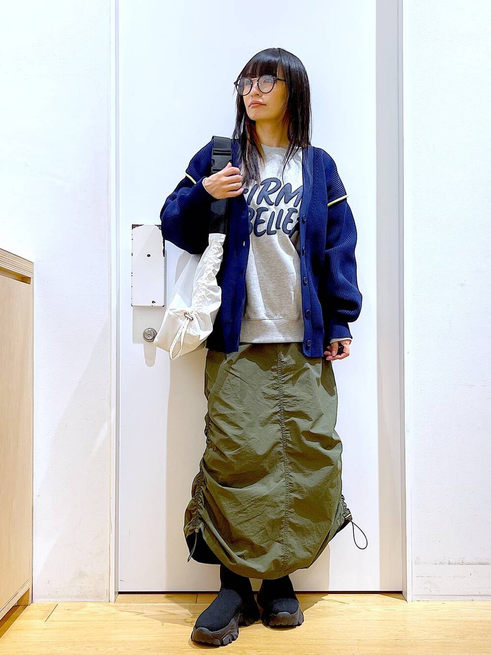 グレー系のスウェット、ブラック系のブーツ、グリーン系のスカートを着用したレディースの冬コーディネートの2枚目の写真