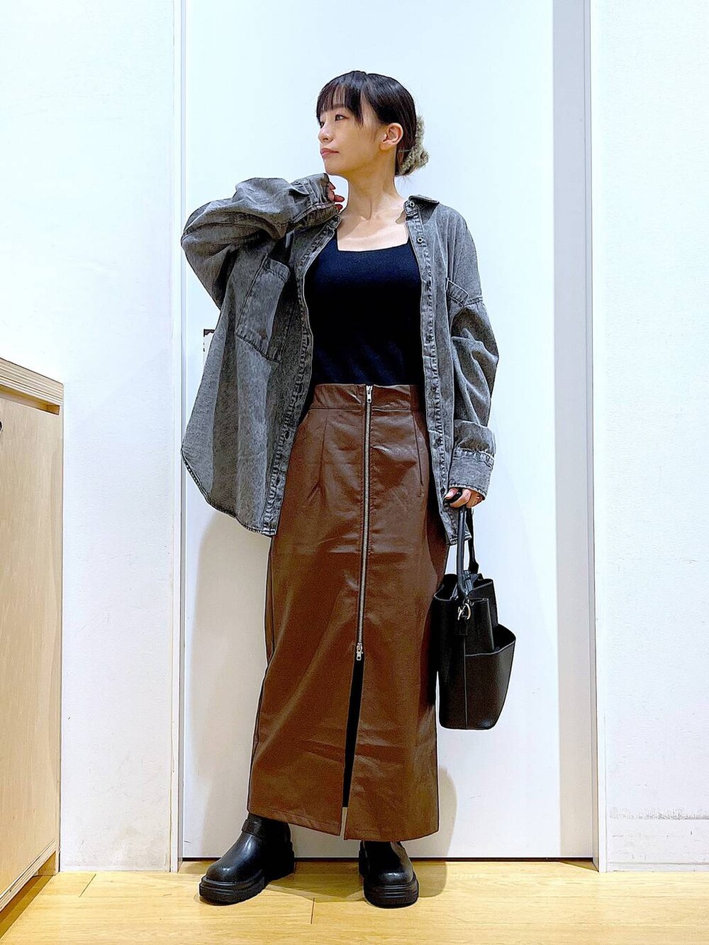 ブラウン系のスカート、ブラック系のニット/セーター、ブラック系のショルダーバッグを着用したレディースの秋コーディネートの2枚目の写真